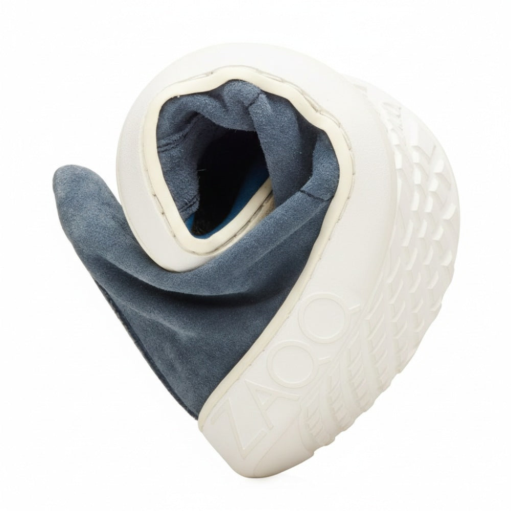 Ein blauer Sneaker ist spiralförmig gedreht, was seine flexible Sohle und das Obermaterial aus weichem Veloursleder hervorhebt. Das strukturierte Muster auf der Sohle wertet das geprägte Wort „ZOOO“ an der Seite auf und lässt dieses ZAQQ QORE Mid Deep Sea-Design wirklich hervorstechen.