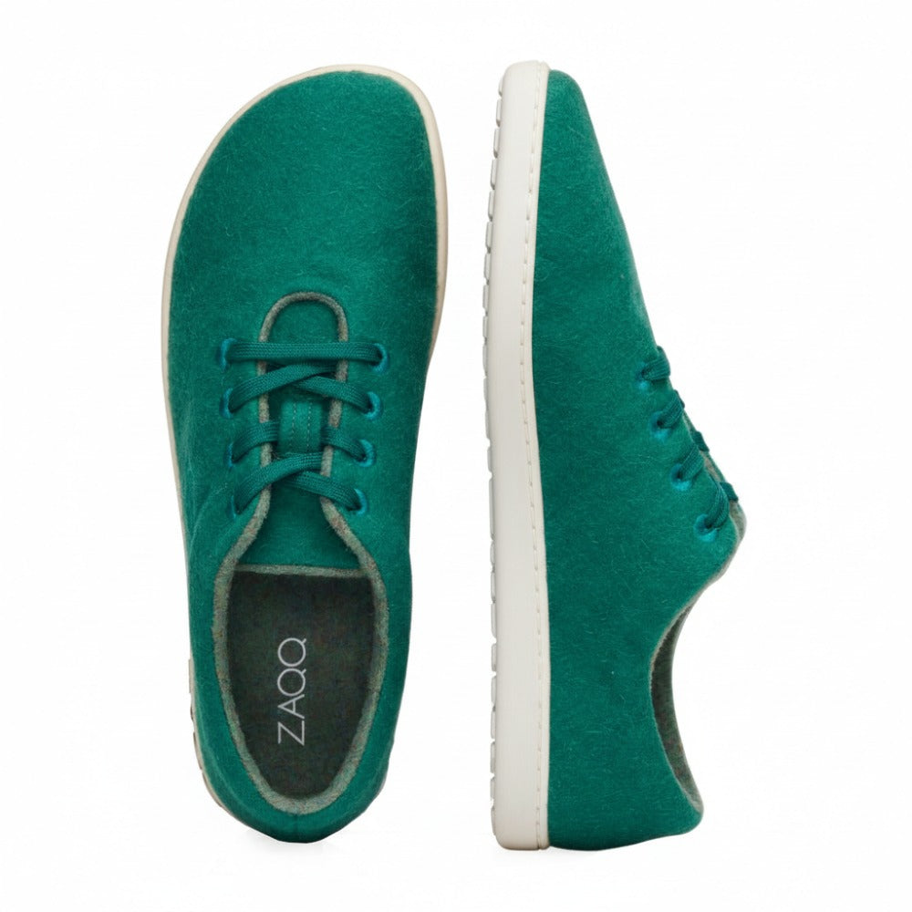 Die LIQE Green Sneaker von ZAQQ im minimalistischen Design sind in Grün mit Schnürsenkeln und weißer Sohle erhältlich. Der Markenname ist deutlich sichtbar an der Seite der Sohle zu sehen. Sowohl von oben als auch von der Seite betrachtet sind diese Schuhe für diejenigen gemacht, die Einfachheit und Komfort schätzen.
