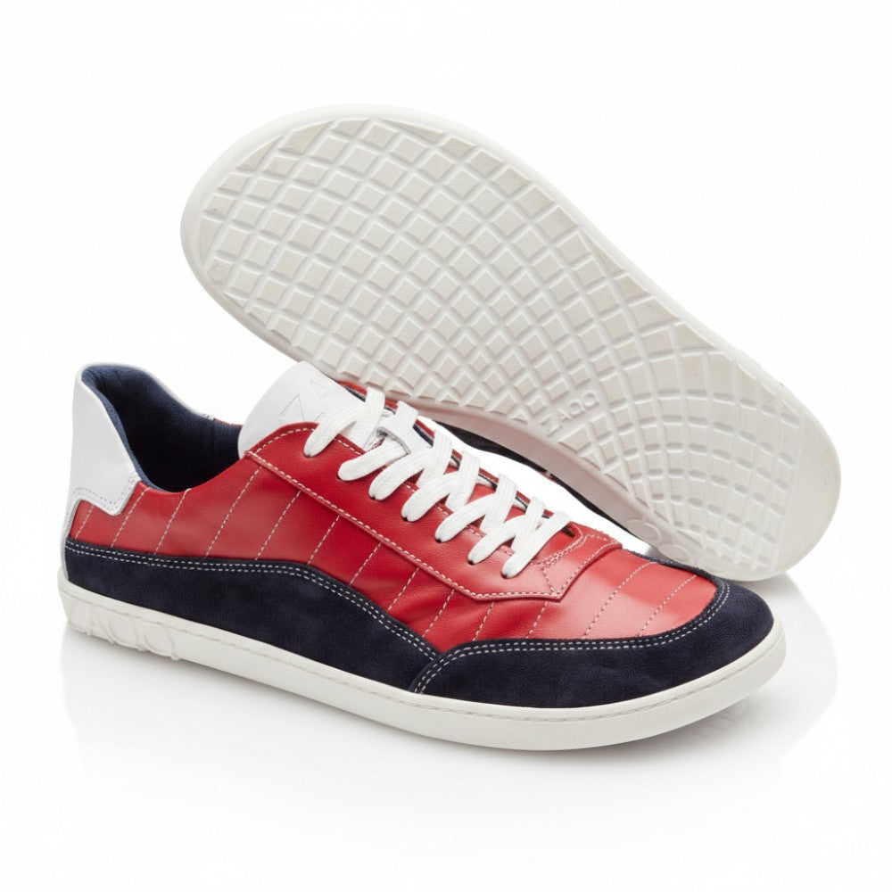 Die QAMPION Navy Red Sneaker von ZAQQ präsentieren ein stilvolles Design mit Obermaterial aus Nappaleder in einer auffälligen Kombination aus Rot und Marineblau, akzentuiert durch weiße Details und Schnürsenkel. Die Sohlen weisen Gittermuster auf, die den Komfort eines Barfußschuhs verkörpern. Das ZAQQ-Branding ist sowohl an der Ferse als auch an der Sohle deutlich zu sehen.