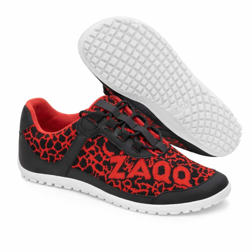 Die QASEY Red Sneaker von ZAQQ sind aus schwarzem und rotem Mesh-Gewebe gefertigt. Diese veganen Barfußschuhe zeichnen sich durch ein strukturiertes Design mit schwarzen Overlays auf Rot aus und tragen den Markennamen ZAQQ auf der Seite. Die weiße Sohle ist flexibel gestaltet und hat eine Gummitextur, die an ein Gitter erinnert, wobei ein Schuh so sichtbar ist, dass seine Unterseite zu sehen ist.