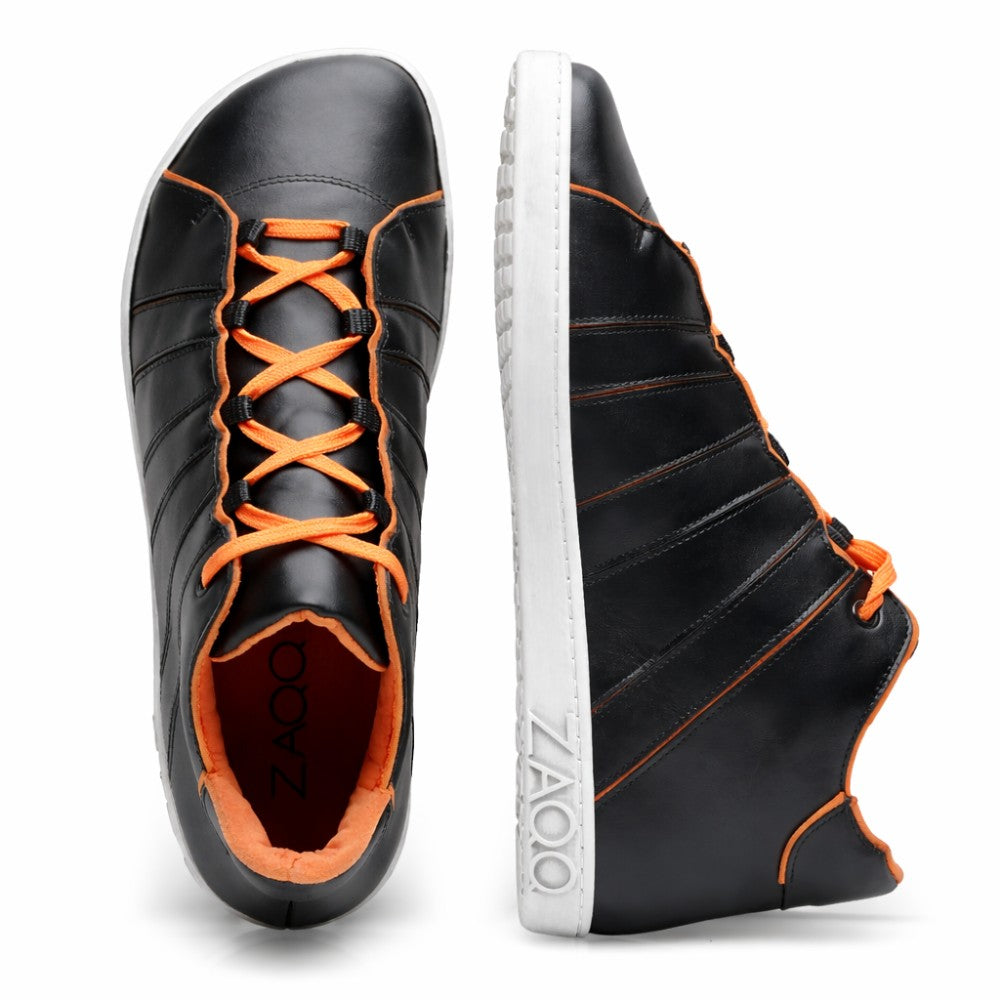 Die QQQ Mid Black Orange Sneaker von ZAQQ haben ein elegantes und dennoch auffälliges Design. Sie sind aus schwarzem Nappaleder gefertigt und haben orangefarbene Schnürsenkel und Nähte. Sie haben markante weiße Kautschuksohlen, auf denen der Markenname ZAQQ deutlich sichtbar an der Seite zu sehen ist. Ein Schuh ist von oben und der andere von der Seite zu sehen.