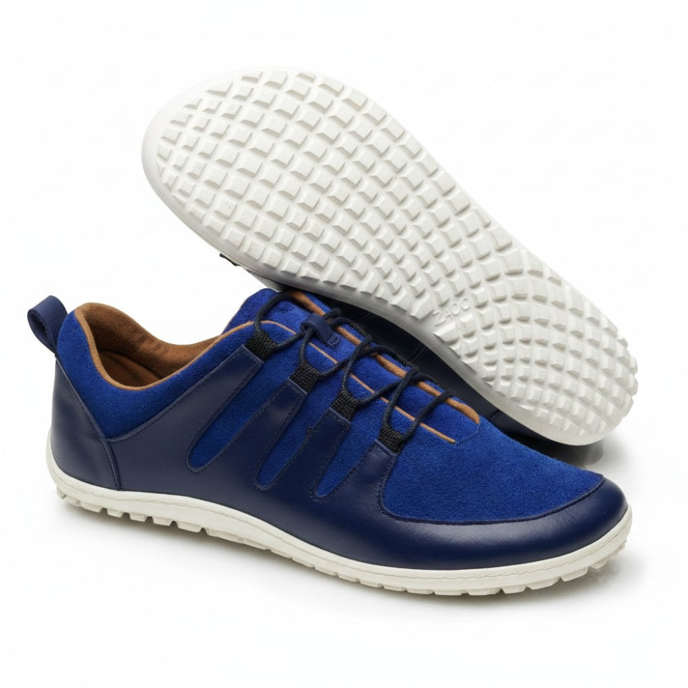 Ein Paar blau-marineblaue SHOQQ Trident-Sneaker von ZAQQ mit weißer Kautschuksohle. Ein Schuh steht aufrecht, während der andere geneigt ist, um das strukturierte Sohlenmuster hervorzuheben. Diese Sneaker zeichnen sich durch ein lässiges und modernes Design aus und eignen sich ideal für den Alltag.