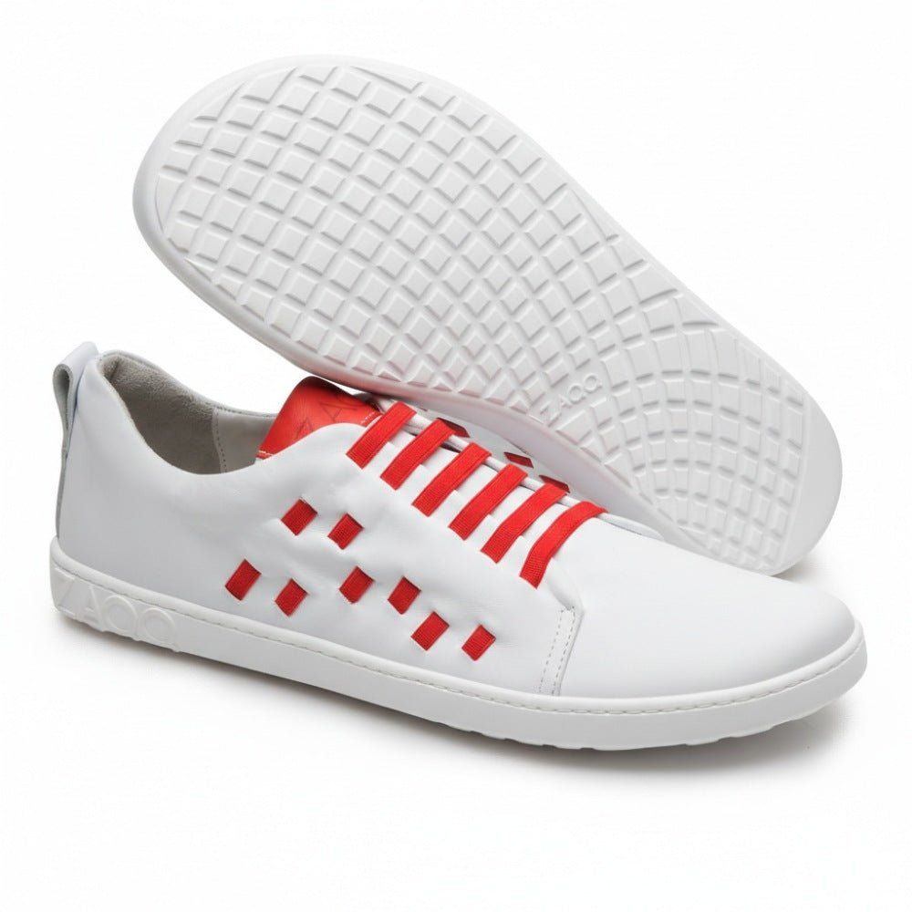 Ein Paar der stylischen STRAQ White Sneaker von ZAQQ mit roten Akzenten und Schnürsenkeln aus hochwertigem Nappaleder. Bei einem Schuh ist das Profil mit Gittermuster für hervorragenden Halt zu sehen, während der Markenname ZAQQ elegant in die Sohle geprägt ist.